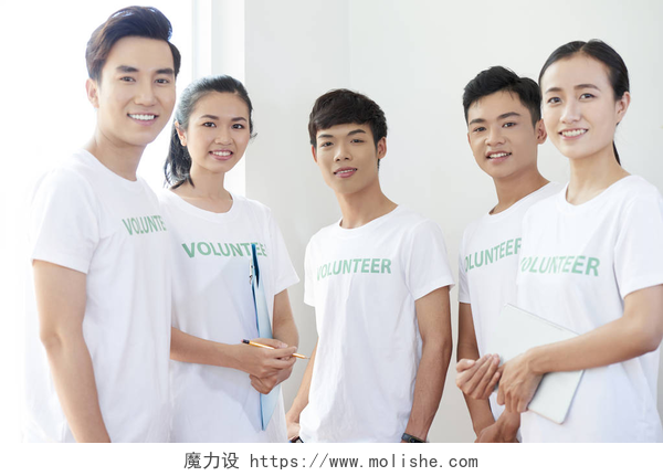 穿白色T恤的年轻志愿者们身着白色T恤的亚洲青少年志愿者站在一起，对着镜头微笑的肖像